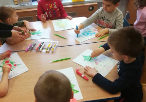 Dzieci kolorują choinki z narysowanymi samodzielnie bombkami.